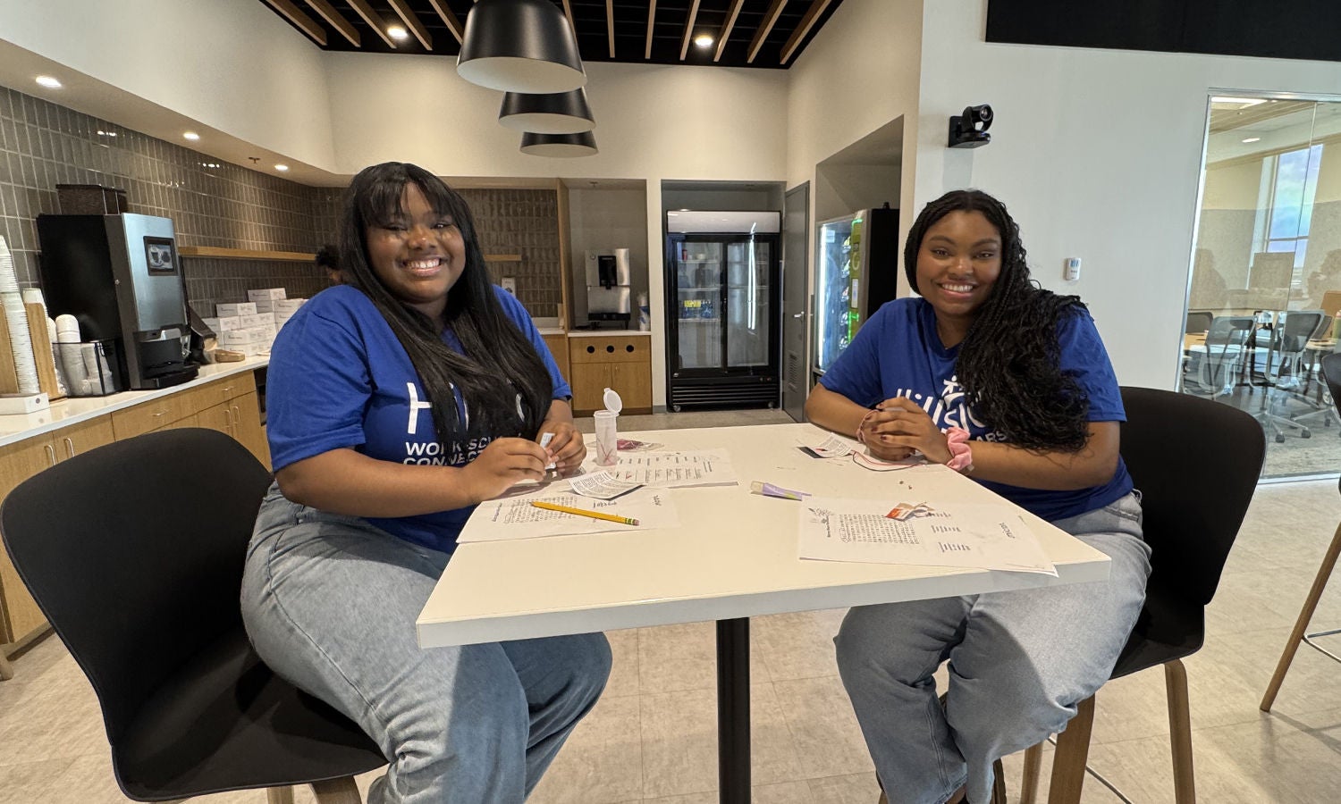 Two students in blue Hillside shirts smile during their hands-on activity.